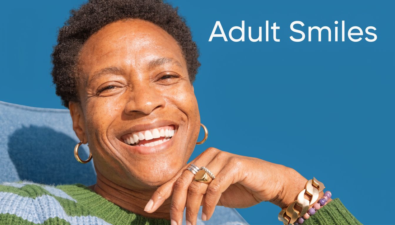 A close-up portrait of a happy smiling adult person wearing stylish jewelry against a solid blue background.
