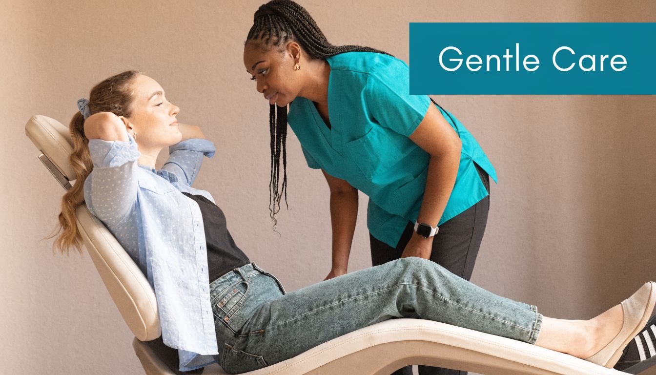 A friendly female dentist in blue scrubs interacting gently with a patient reclining in a dental chair.