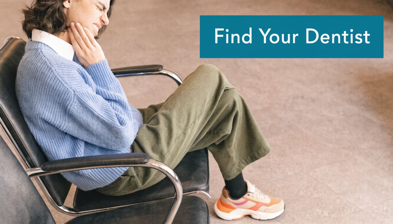 A woman sitting in a waiting room chair holding her jaw in visible pain and discomfort.