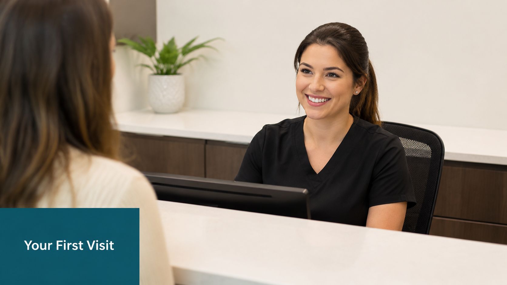 A smiling dental receptionist greets a patient at the front desk of a modern dental clinic.